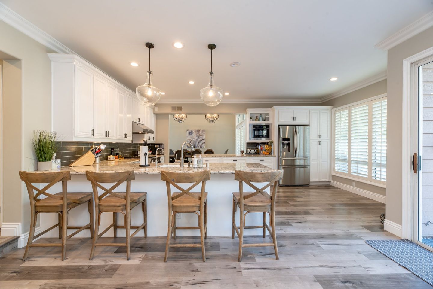 Bright modern kitchen with white cabinets, island seating, and large windows letting in natural light